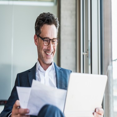 Portrait of laughing businessman with documents 